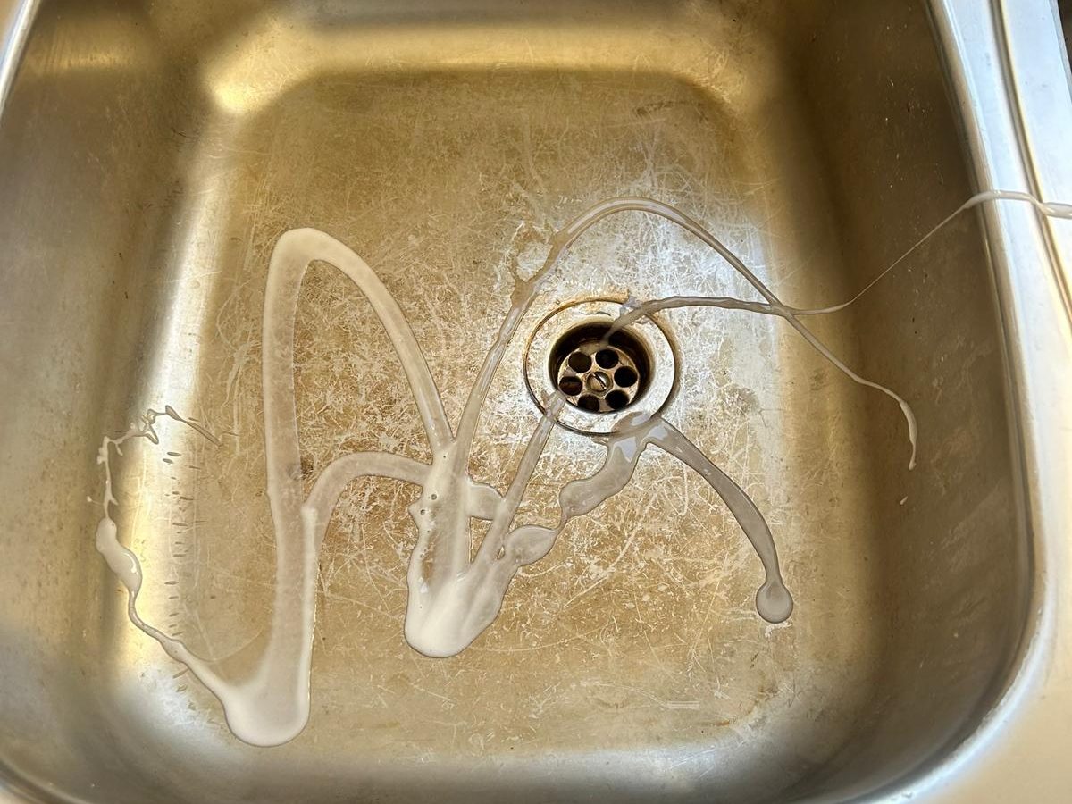 Stained stainless steel kitchen sink with limescale and residue before cleaning