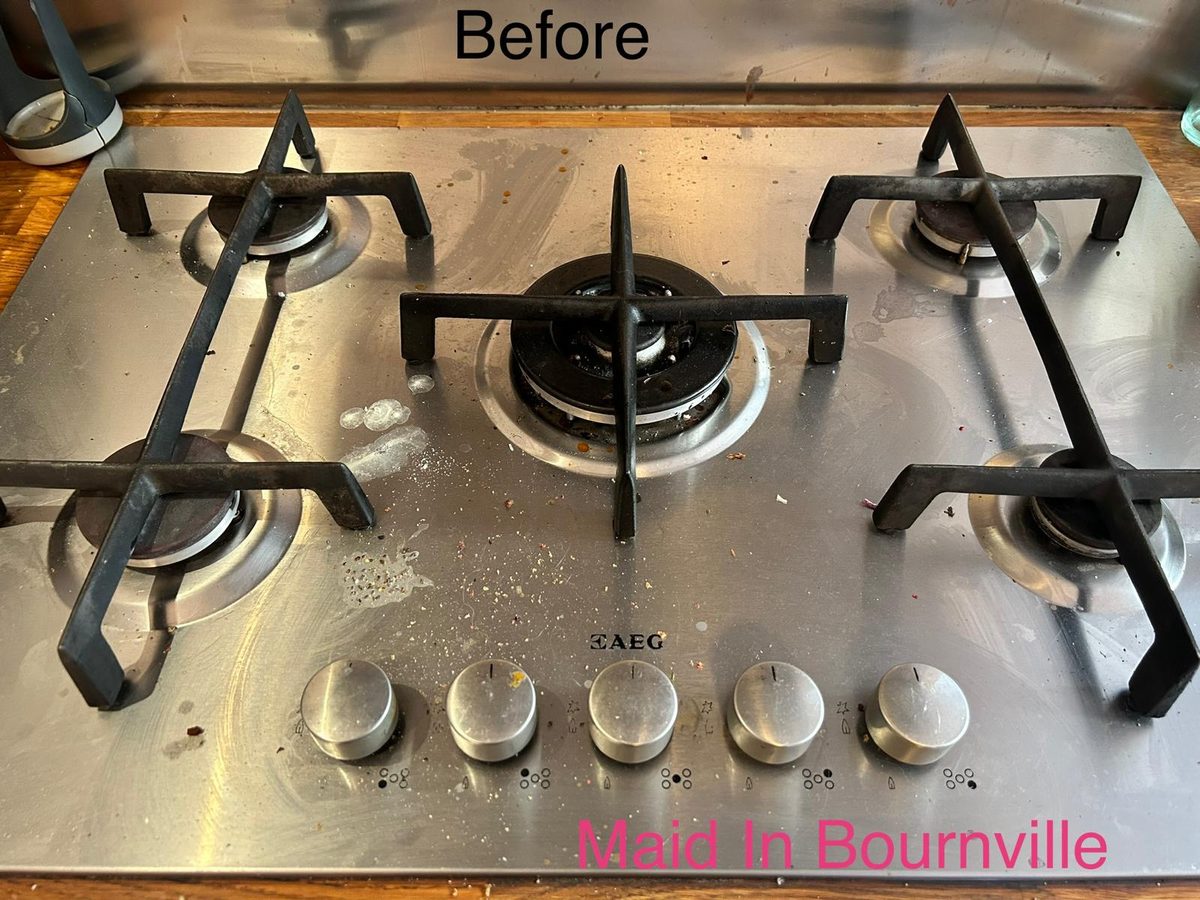 Five-burner stainless steel range hob with grease splashes and crumbs before cleaning